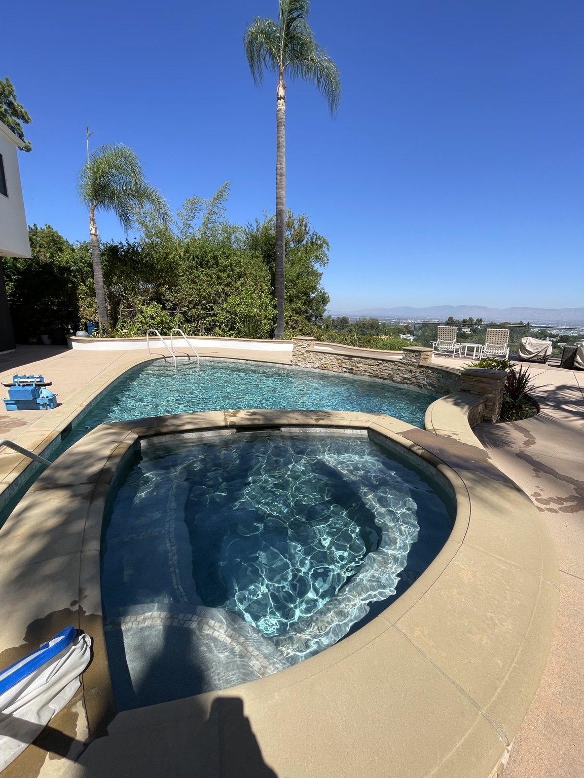 Real residential pool and spa with tall palms and hillside views